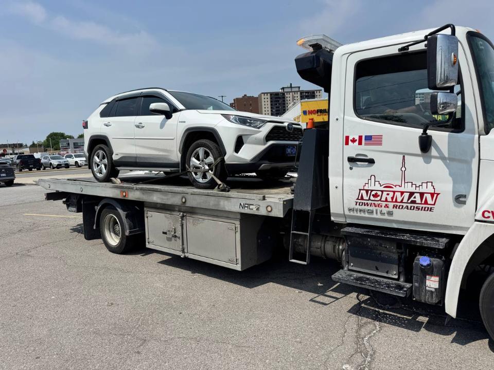 Tow truck removing unauthorized car from private property in Peel Region