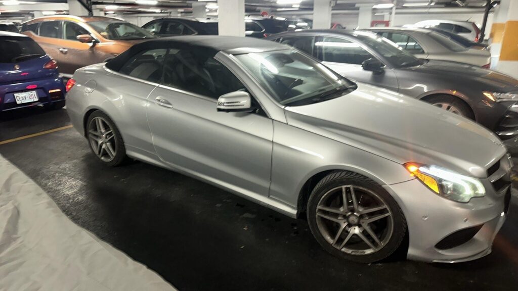 Rear perspective of a Mercedes-Benz E350 Cabriolet being prepared for towing in a condo parking lot.
